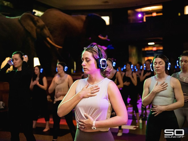Women participating in an indoor yoga class with Sound Off silent disco headphones