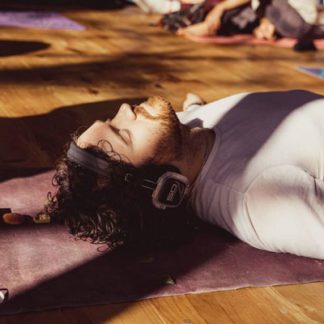 Man lying on a mat experiencing psychedelic-assisted therapy while wearing Sound Off headphones.