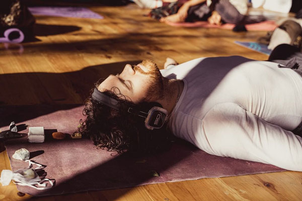 Man lying on a mat experiencing psychedelic-assisted therapy while wearing Sound Off headphones.